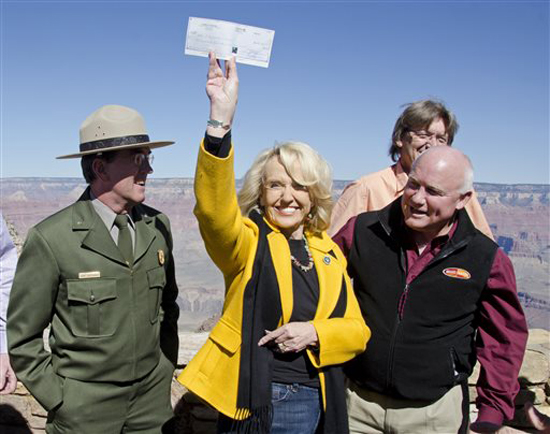 This image provided by the National Park service shows Arizona Governor Jan Brewer holding a check for $426,500 dollars presented to her by the town of Tusayan, Ariz., as partial payment to the park, Saturday Oct. 12, 2013 at Grand Canyon National Park, Ariz. Also shown, from left, Grand Canyon National Park Superintendent Dave Uberuaga; Brewer; Tusayan, Ariz., Mayor Greg Bryan and Tusayan Councilman, Craig Sanderson, rear. The National Park Service announced that it has entered into an agreement with the State of Arizona that will allow Grand Canyon National Park to re-open and temporarily operate during the government shutdown. / AP Photo/ National Park Service, Michael Quinn