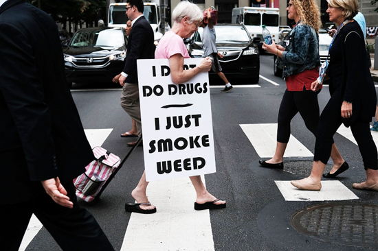 PHILADELPHIA, PA - JULY 28: A woman walks with a sign supporting legalizing marijuana during the Democratic National Convention (DNC) on July 28, 2016 in Philadelphia, Pennsylvania. The convention officially began on Monday and has attracted thousands of protesters, members of the media and Democratic delegates to the City of Brotherly Love.  /Photo by Spencer Platt/Getty Images