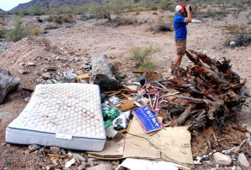  Joe Hoover uses binoculars to read graffiti left at the peak of a nearby mountain. A pile of trash was left just off the road on land that would be included in the Palo Verde Regional Park./Katie Campbell/Dispatc