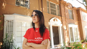 A member of the Los Angeles Tenants Union stands in front of a Hollywood apartment building that has been approved for conversion into a hotel, on June 29. /Los Angeles Times
