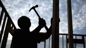  The silhouette of a contractor is seen hammering wood framing for a house under construction in the Norton Commons subdivision of Louisville, Kentucky. /Luke Sharrett | Bloomberg | Getty Images 